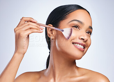 Buy stock photo Shot of a young attractive woman applying makeup against a grey background