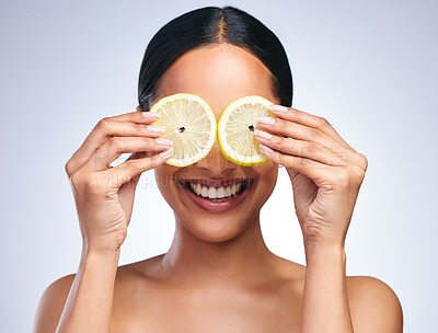 Buy stock photo Portrait of an attractive young woman posing with a sliced lemon against a grey background