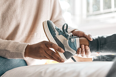 Buy stock photo Cropped shot of an unrecognizable helping her son with his shoes while sitting on a bed at home