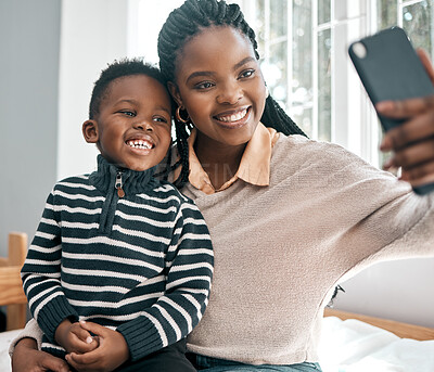 Buy stock photo Cropped shot of an attractive young woman and her adorable son taking selfies while sitting on a bed at home