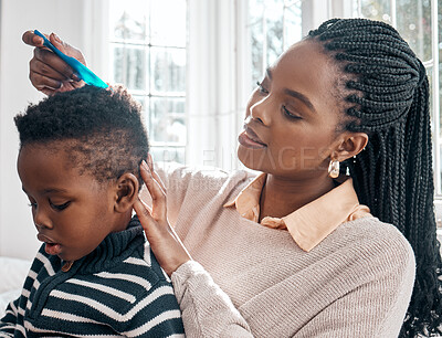 Buy stock photo Cropped shot of an attractive young woman combing her son's hair while sitting on a bed at home