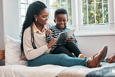 Buy stock photo Shot of a little boy and his mother looking at something on a digital tablet while sitting at home