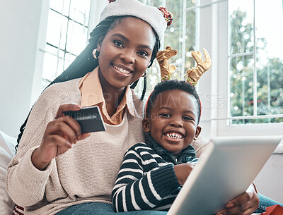 Buy stock photo Shot of a woman holding her credit card and holding a digital tablet while sitting with her son during Christmas time