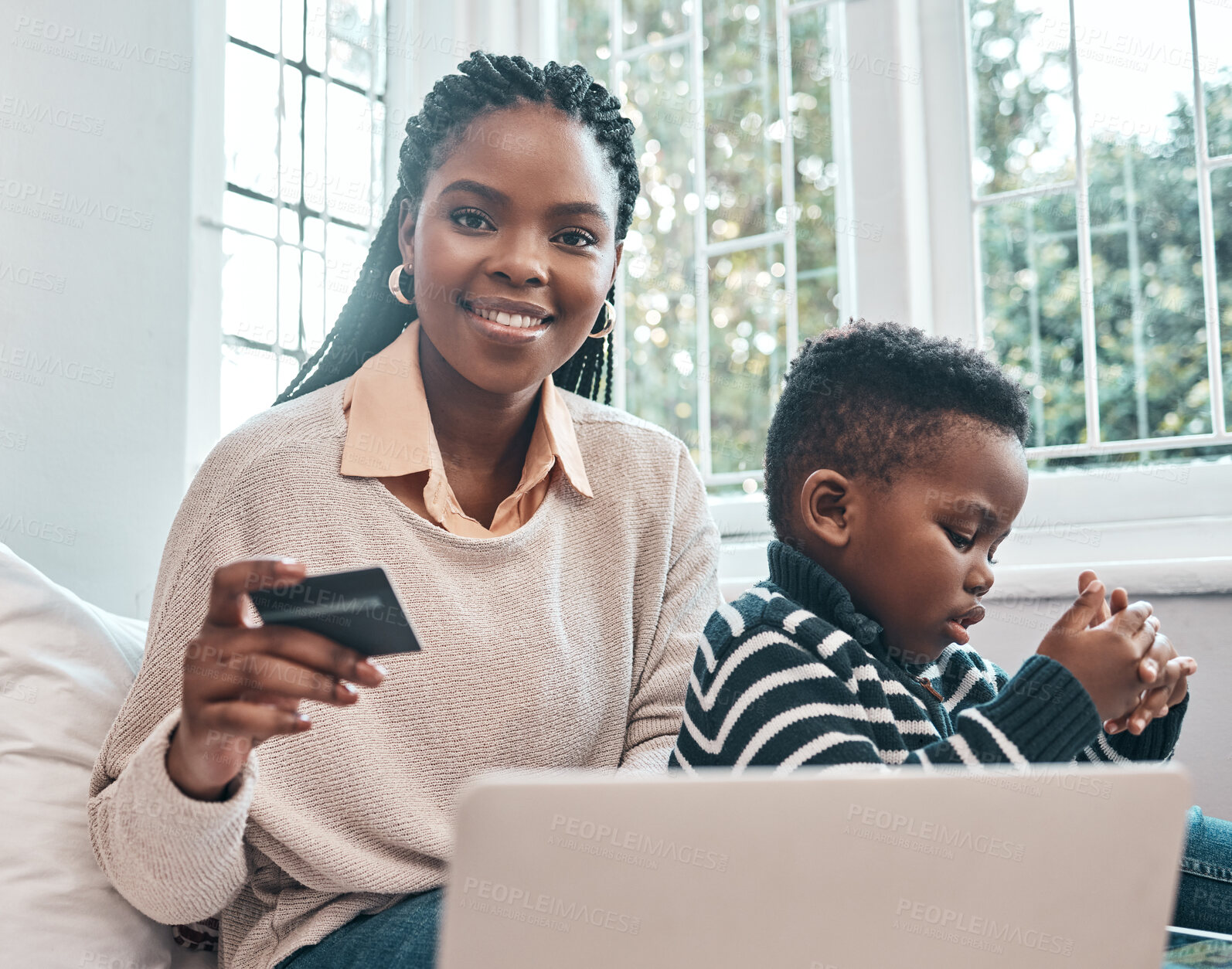 Buy stock photo Shot of a woman holding her credit card while using her laptop and sitting with her son