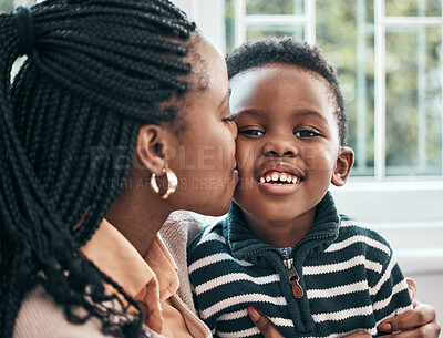 Buy stock photo Shot of a woman kissing her son on his cheek while sitting at home