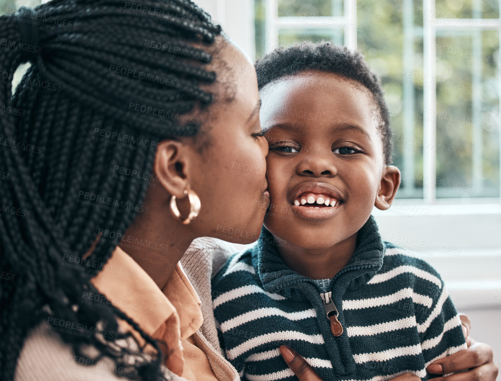 Buy stock photo Shot of a woman kissing her son on his cheek while sitting at home