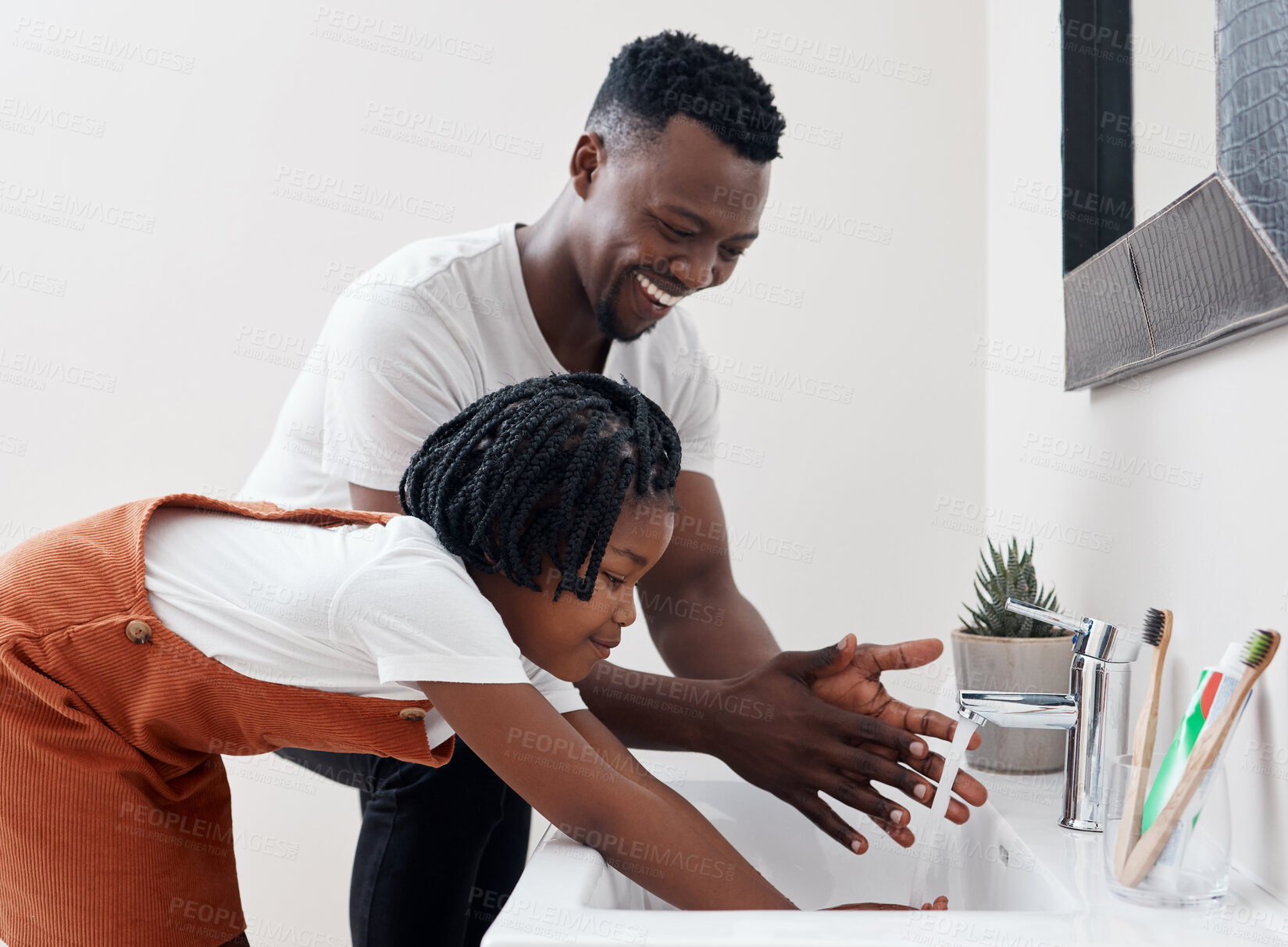 Buy stock photo Shot of a young father helping his daughter wash her hands in the bathroom at home