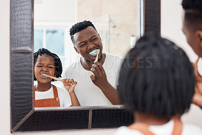 Buy stock photo Shot of a young father bonding with his daughter while they brush their teeth in the bathroom at home