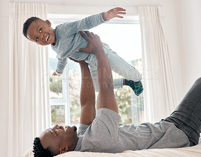 Buy stock photo Cropped shot of an adorable little boy playing with his father on a bed at home