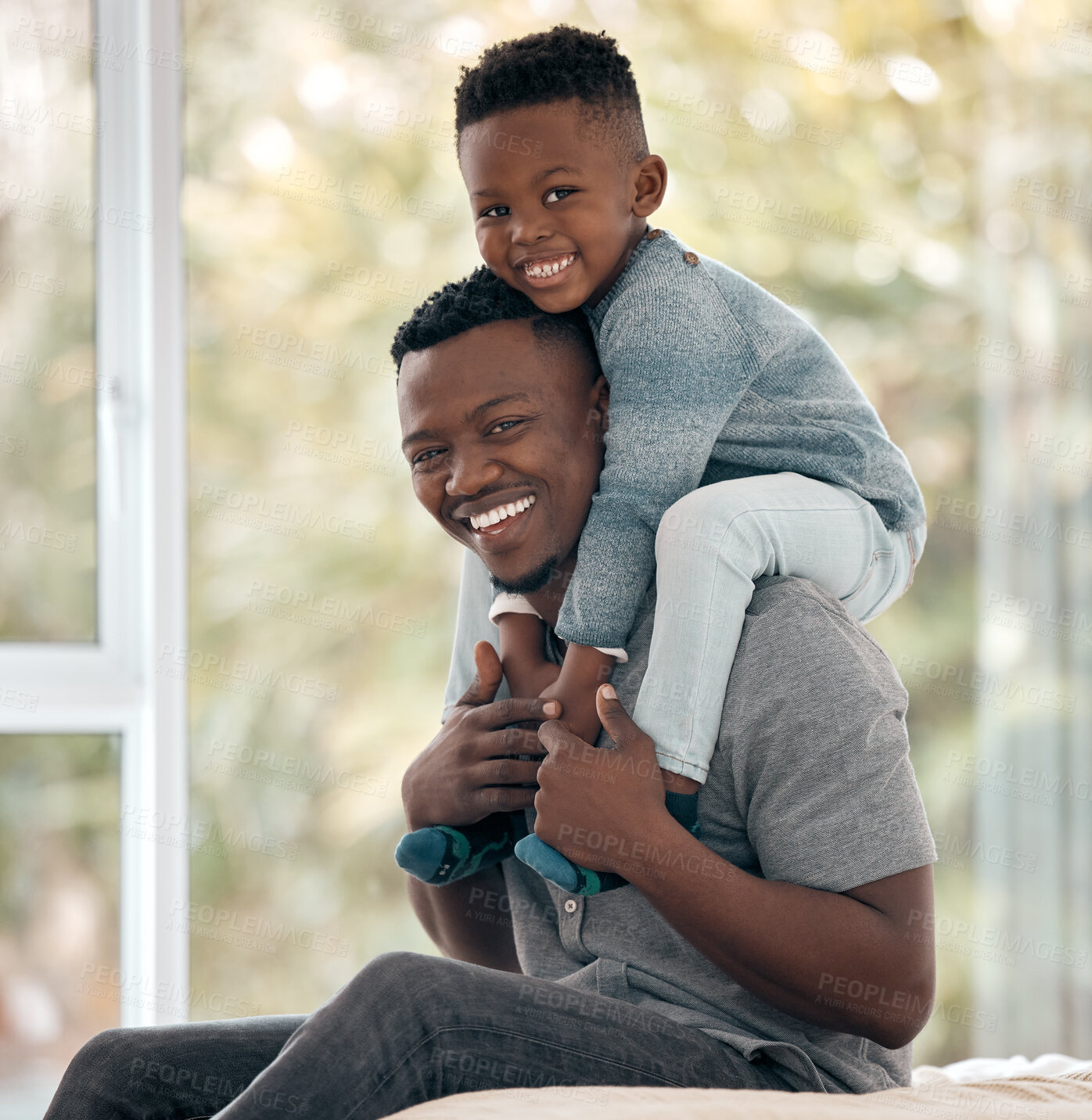 Buy stock photo Cropped portrait of a handsome young man sitting on the bed at home with his son on his shoulders