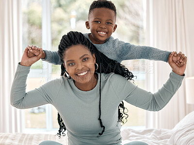 Buy stock photo Cropped portrait of an attractive young woman sitting on the bed at home with her son on her back