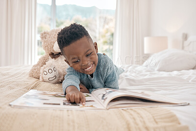Buy stock photo Full length shot of an adorable little boy reading a book on a bed at home