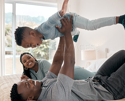 Buy stock photo Cropped shot of an adorable little boy playing with his father on a bed at home while his mother watches on