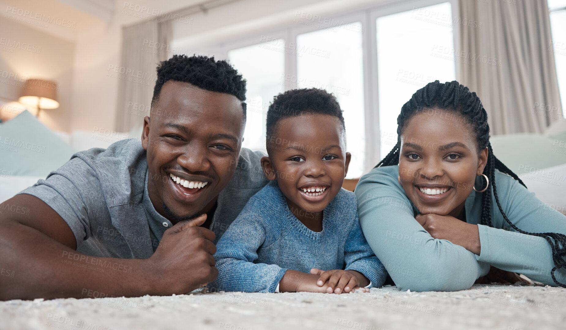 Buy stock photo Shot of a young couple lying on the living room floor and bonding with their son at home