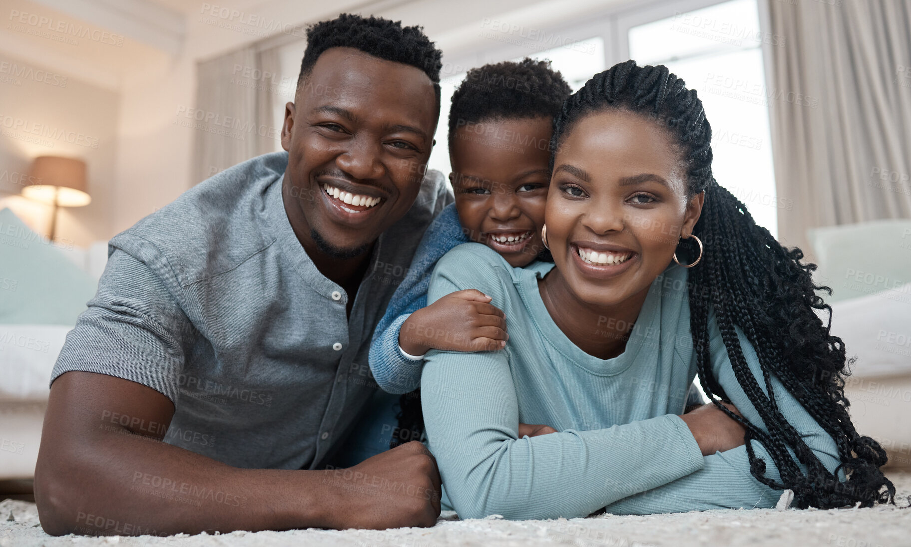 Buy stock photo Shot of a young couple lying on the living room floor and bonding with their son at home