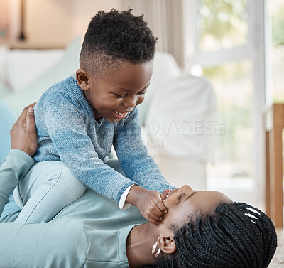 Buy stock photo Shot of a young mother lying on the the living room floor and bonding with her son at home