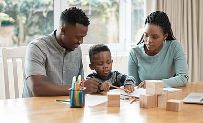 Buy stock photo Shot of a young couple sitting at the table with their son and helping him draw