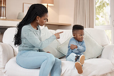 Buy stock photo Shot of a young mother sitting in the living room at home and discipling her son