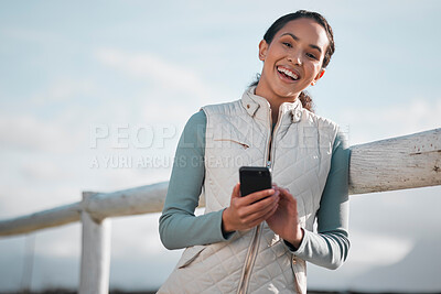 Buy stock photo Shot of an attractive young woman standing alone on her farm and using her cellphone