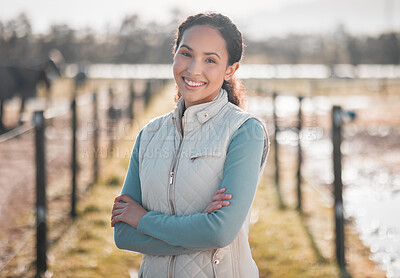 Buy stock photo Shot of an attractive young woman standing alone on her farm with her arms folded