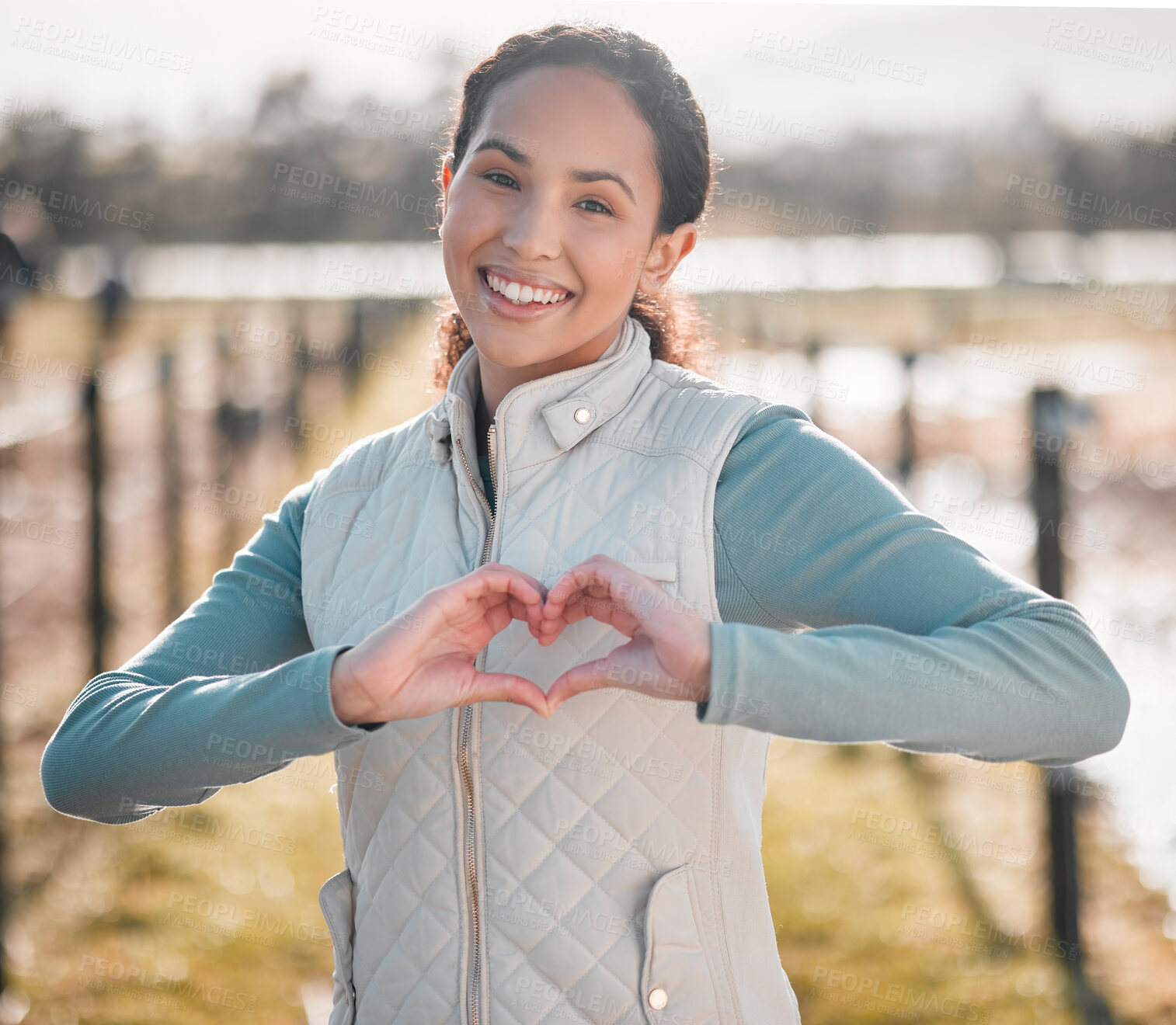 Buy stock photo Shot of an attractive young woman standing alone on her farm and making a heart shaped gesture
