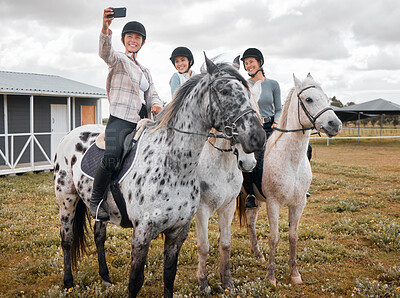 Buy stock photo Cropped shot of three attractive young women taking selfies while horse riding on a farm