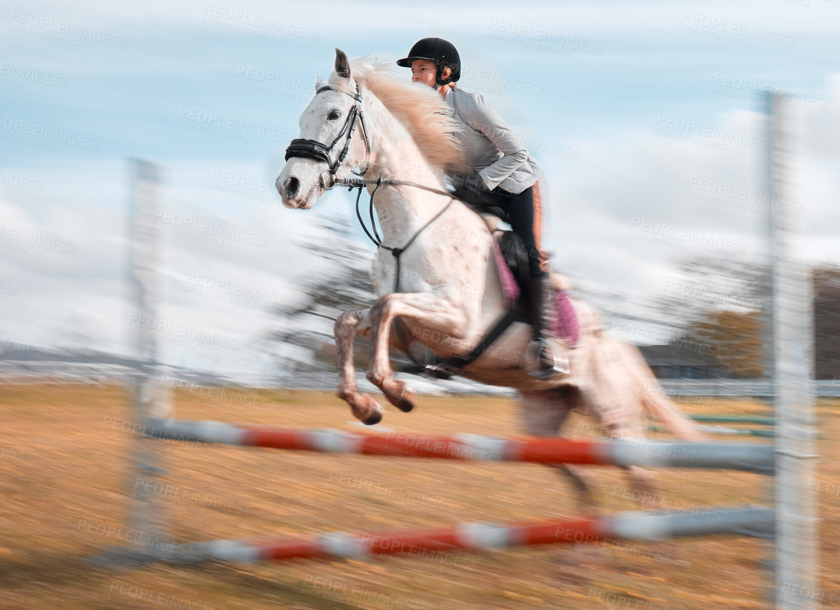 Buy stock photo Shot of a young rider jumping over a hurdle on her horse