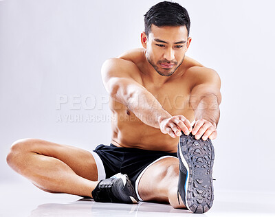 Buy stock photo Shot of a young man stretching his leg against a studio background