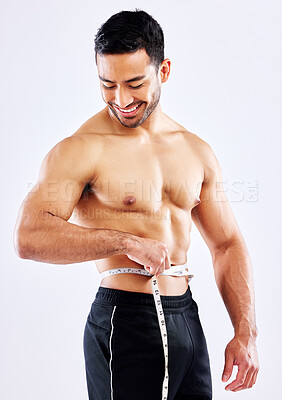 Buy stock photo Shot of a male athlete measuring his waist against a white studio background