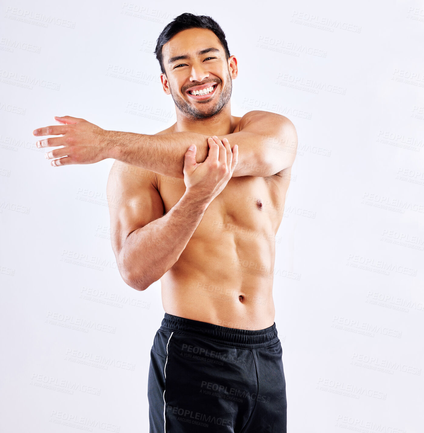 Buy stock photo Shot of a young man stretching his arms before a workout against a studio background