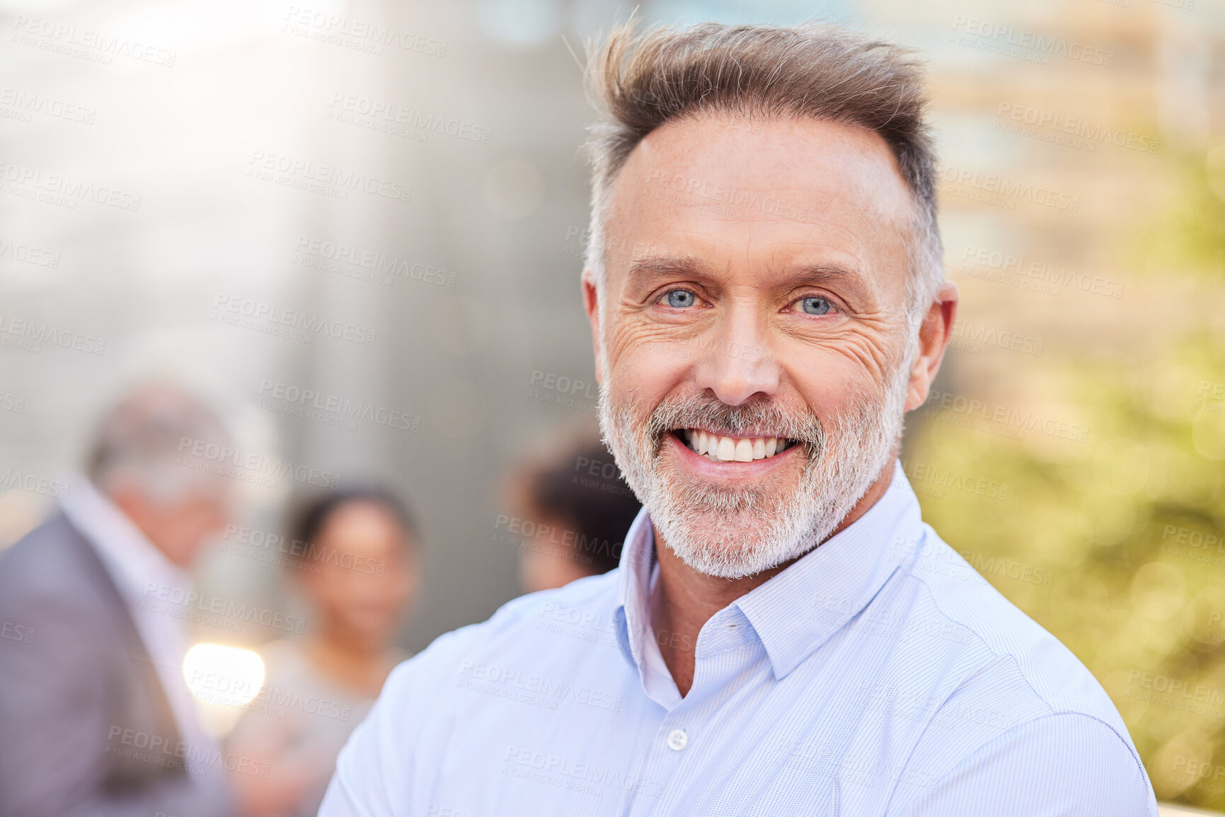 Buy stock photo Shot of a handsome mature businessman standing outside while his colleagues stand behind him