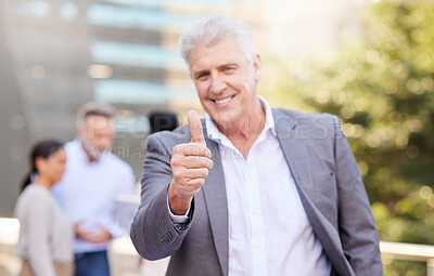 Buy stock photo Shot of a mature businessman standing outside and showing a thumbs up while his colleagues discuss behind him