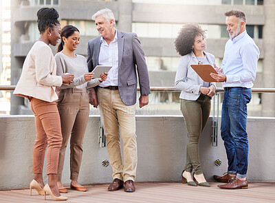 Buy stock photo Full length shot of a diverse group of businesspeople standing on the balcony outside and discussing while using digital tablets