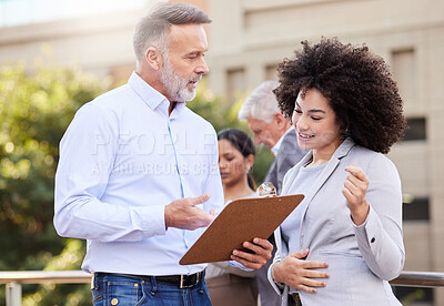 Buy stock photo Shot of two businesspeople standing outside on the balcony and discussing while using a clipboard