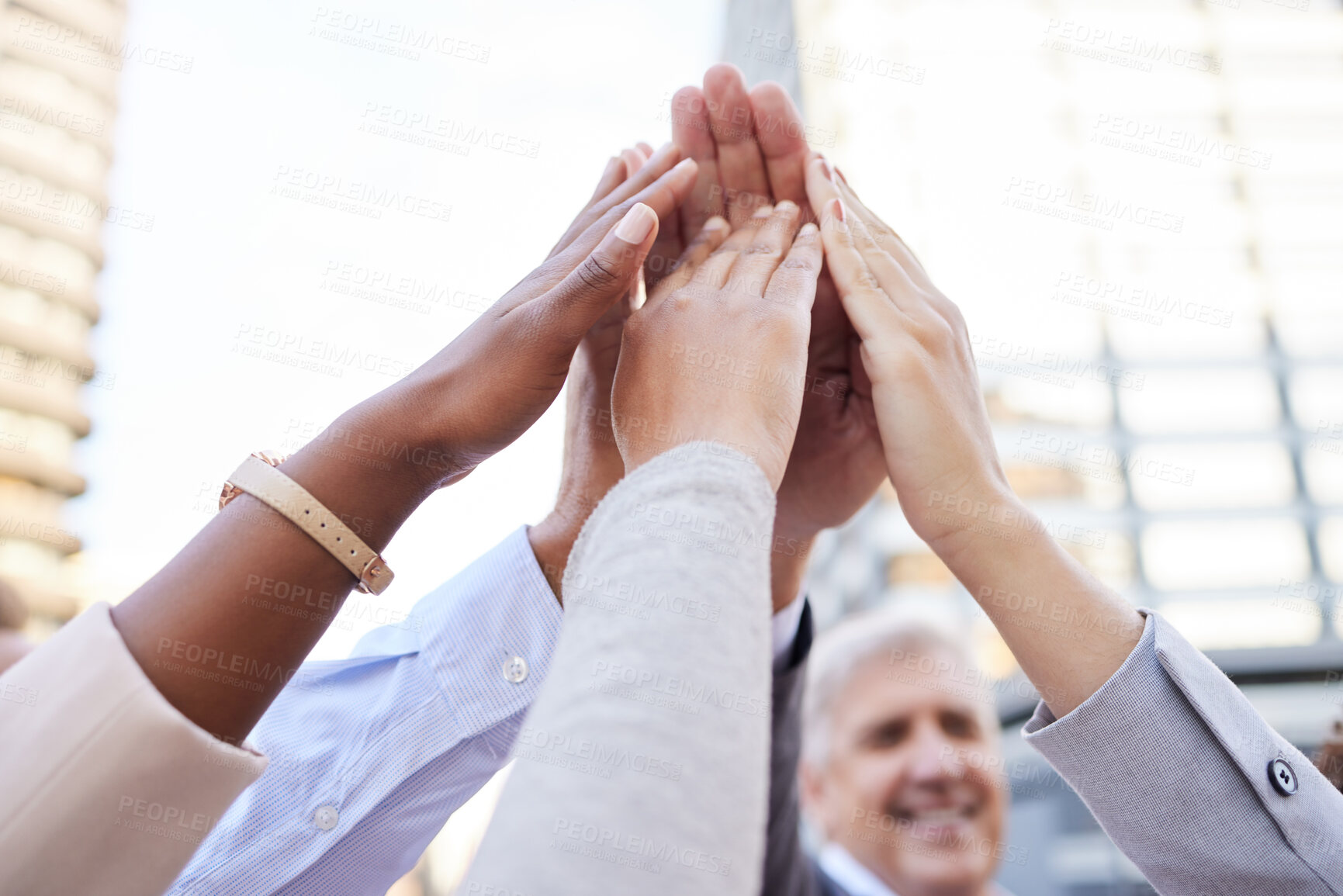 Buy stock photo Shot of an unrecognisable group of businesspeople huddled outside together with their arms raised and hands in the middle