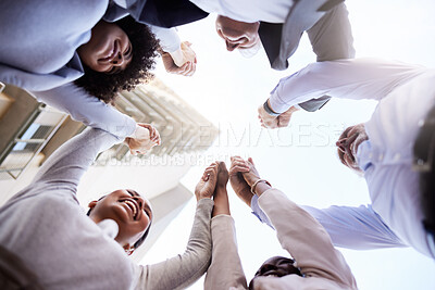 Buy stock photo Low angle show of a diverse group of businesspeople huddled outside together and holding hands