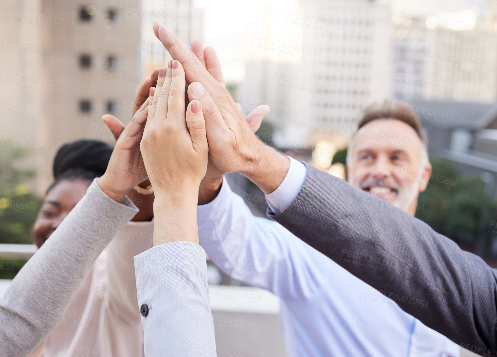 Buy stock photo Shot of a diverse group of businesspeople huddled outside together with their arms raised and hands in the middle