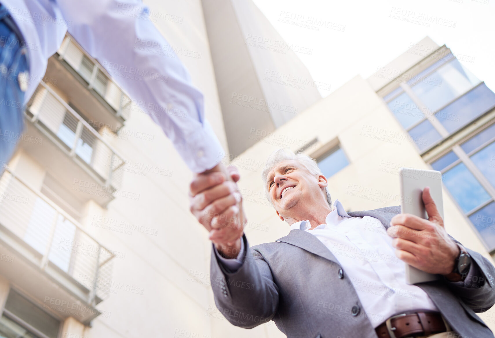 Buy stock photo Low angle shot of two businessmen standing outside on the balcony together and shaking hands