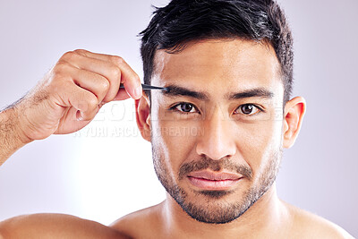 Buy stock photo Studio shot of a handsome young man tweezing his eyebrows