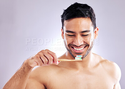 Buy stock photo Studio shot of a handsome young man holding up his toothbrush
