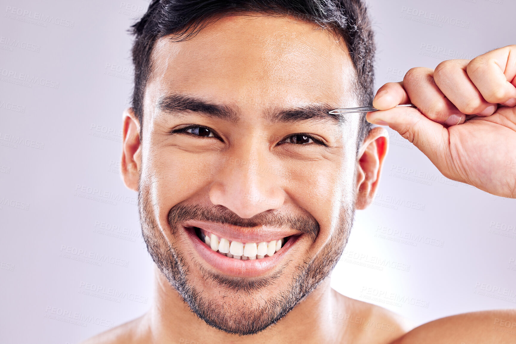 Buy stock photo Studio shot of a handsome young man tweezing his eyebrows