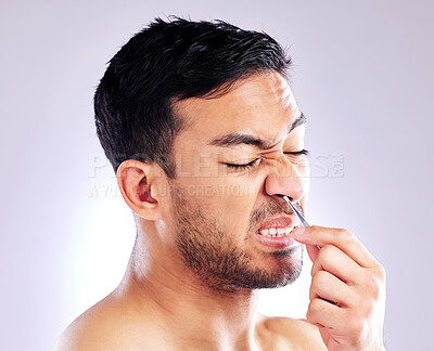 Buy stock photo Studio shot of a handsome young man plucking his nose hair