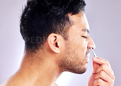 Buy stock photo Studio shot of a handsome young man plucking his nose hair
