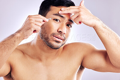 Buy stock photo Studio shot of a handsome young man tweezing his eyebrows
