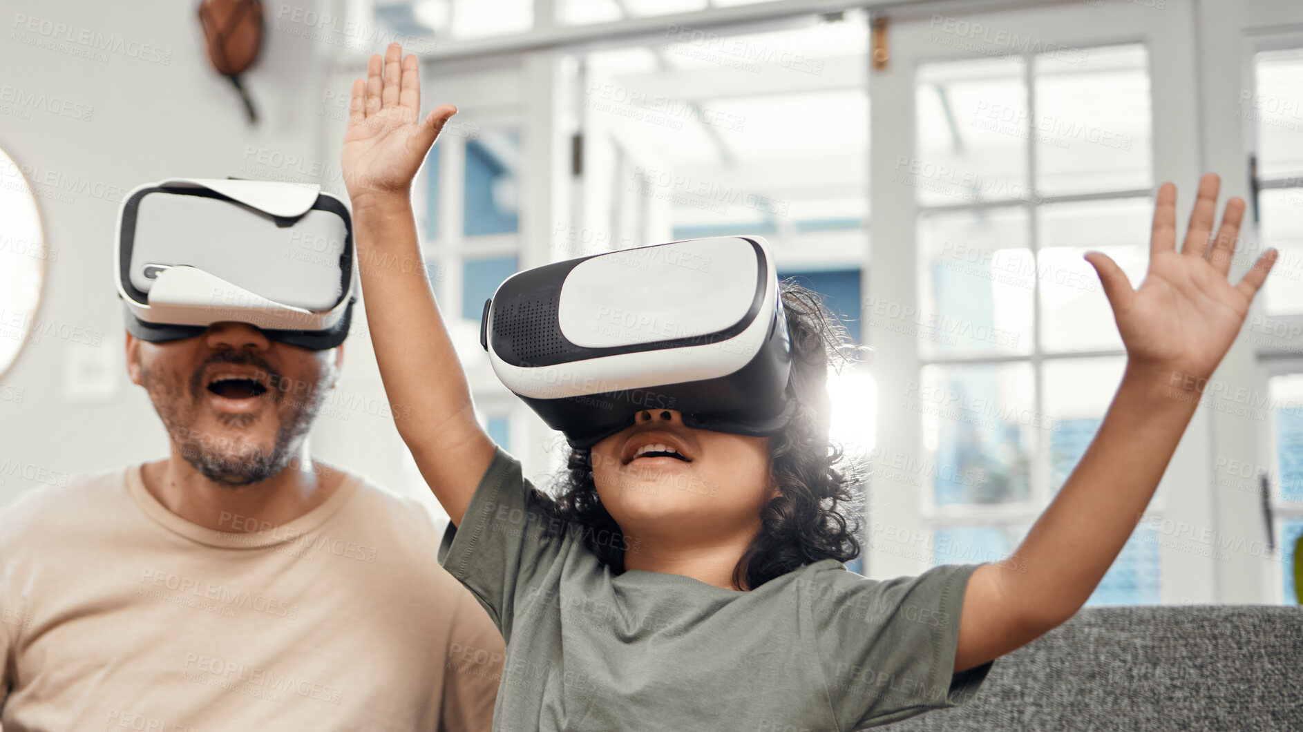 Buy stock photo Shot of a little boy and his father wearing VR glasses at home