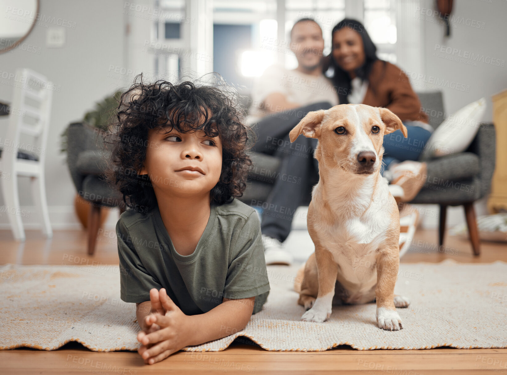 Buy stock photo Shot of a little boy bonding with his dog while his parents sit in the background