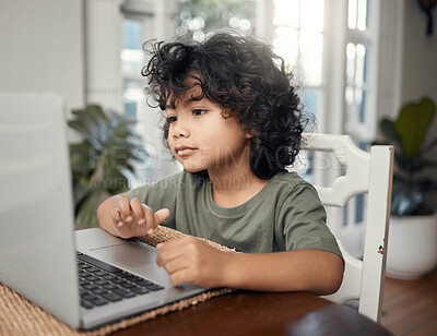 Buy stock photo Shot of an adorable little boy using a laptop while sitting at home