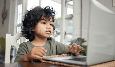 Buy stock photo Shot of an adorable little boy using a laptop while sitting at home