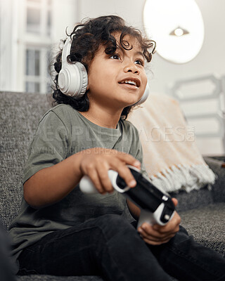 Buy stock photo Shot of an adorable little boy wearing headphones while playing video games at home