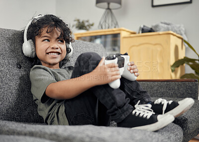 Buy stock photo Shot of an adorable little boy wearing headphones while playing video games at home